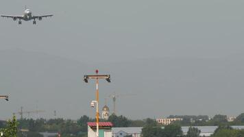 Front view of a passenger jet with no visible airline branding on final approach for landing over the city video