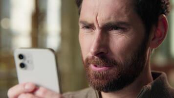 Close up angry middle-aged business man texting message mobile phone in hands typing smartphone annoyed furious man businessman stressed male guy in office displeased chatting negative sms cellphone video