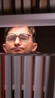 vertical Student searching for book on library shelf at night video