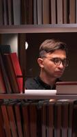 vertical Priest putting book on bookshelf in church library video
