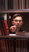 vertical Young man praying with rosary in library setting video