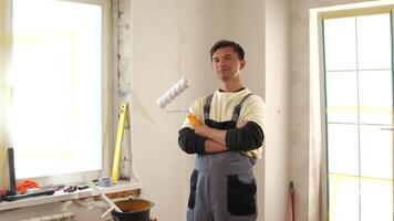 A man in overalls standing in a room with a paint roller video