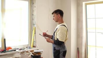 A man is standing in front of a window with a clipboard video