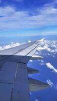 Window view during airplane takeoff, looking out over the wing as the aircraft ascends above the coastline. Scenic view of ocean, clouds, and horizon. video