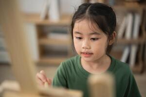 Young girl focused on painting at easel, creative expression in art studio, colorful brush strokes, childhood creativity, passion for art and learning photo
