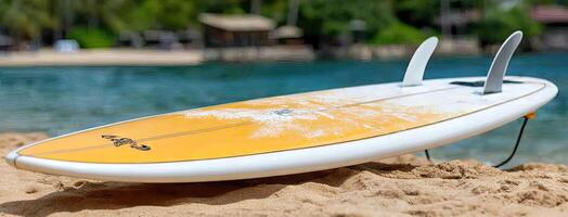 A yellow surfboard sitting on the sand near the water photo