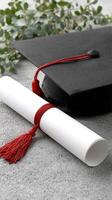 A graduation cap and diploma on a concrete surface photo