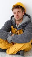 A man in yellow overalls and hard hat sitting on the floor photo