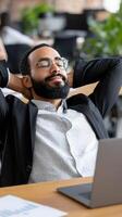 A man with glasses and a beard is relaxing in front of a laptop photo