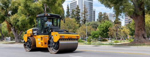 A yellow and black road roller on a city street photo
