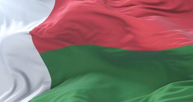 Flag of Madagascar waving at wind in slow in blue sky, loop video