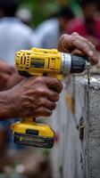 A man is using a drill to drill a hole in a concrete wall photo