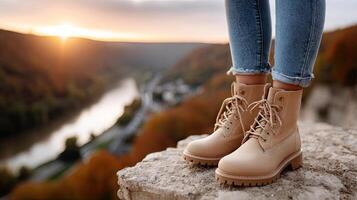 A woman's legs in boots standing on a rock overlooking a river photo