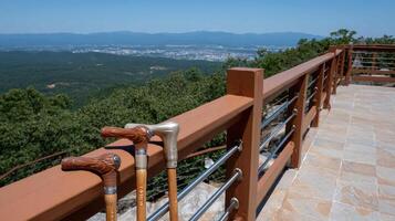 Two wooden walking sticks on a railing overlooking the mountains photo