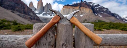 Two wooden tools on a wooden fence with mountains in the background photo