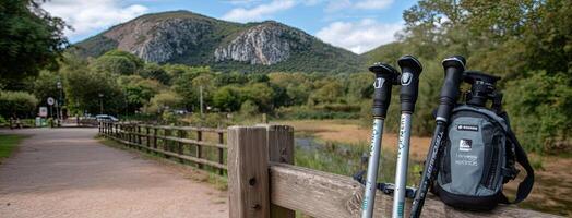 Two hiking poles leaning against a fence with a bag photo