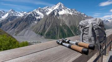 A backpack and two hiking poles sit on a wooden bench overlooking a mountain range photo