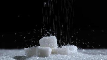 cube sugar and white granulated sugar pouring, symbolizing excessive sugar consumption, diabetes and health risks, health awareness, granulated sugar for sweetness food, ingredient dessert video