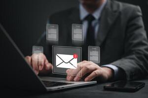 Email marketing concept - business man using laptop with email icons on screen photo