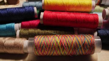 Close-up of vibrant multicolored threads spools arranged on a soft fabric surface in cozy lighting video