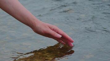 Calm hand gently touching clear water surface in a natural river environment during peaceful moment video