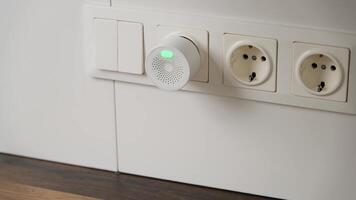 Hand Installing a Compact Gas Detector into Electrical Outlet for Home Safety and Hazard Prevention video