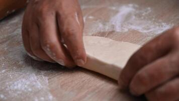 Close-up of hands skillfully shaping dough on a floured wooden surface in a warm kitchen setting video