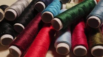Close-up of colorful sewing thread spools highlighting vibrant textures and rich fabrics in a creative workspace video