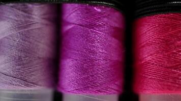 Close-up of Colorful Sewing Thread Spools in Vibrant Red, Lavender, and Magenta Shades on Soft Focus Background video