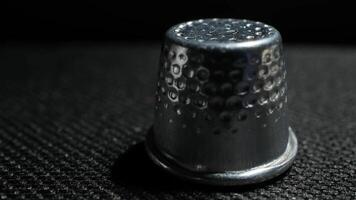 Close-up of a vintage metal thimble on textured dark surface with moody lighting and shadows video