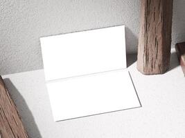 Business card mockup atop a stone with rough textures, surrounded by rustic wooden logs. photo