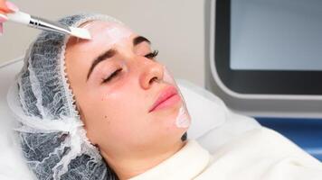 Professional cosmetologist makes a moisturizing mask on the face in a beauty salon. Spa and relaxation concept. photo