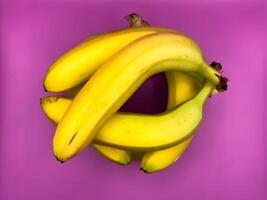 Jenga game of eight bright yellow bananas lying on purple background, top view, center of image photo