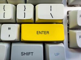A computer keyboard with an yellow Enter photo