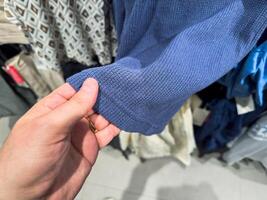 Male white hand checks the quality of clothes in the store before buying photo