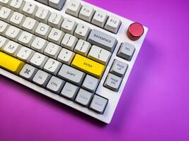 Modern mechanical keyboard isolated with red button on purple background. Minimal style and design keyboard. Colorful key cap. photo