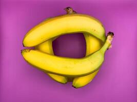 Jenga game of six bright yellow bananas lying on purple background, top view, center of image photo