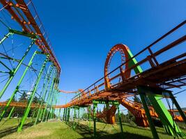Orange roller coaster at an amusement park with cloudy blue sky, hang out and have fun outdoor at theme park, fisheye photo
