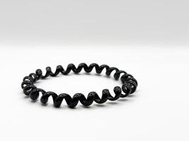 Black glossy silicone hair elastic spiral macro shot on white background front view photo