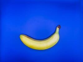 A bright yellow banana lies on a bright blue background at the bottom of the image, top view photo