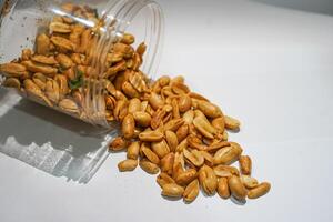 A jar of peanuts on a white surface photo
