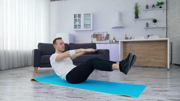 Man doing physical exercise at home. Young man practices on a mat in the modern kitchen during quarantine. Sport at home. video