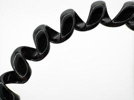 Part of black hair elastic made of glossy silicone in the form of a spiral macro shot on a white background top view photo