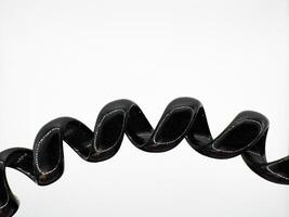 Part of a black hair elastic made of glossy silicone in the form of a spiral macro shot on a white background in the center top view photo