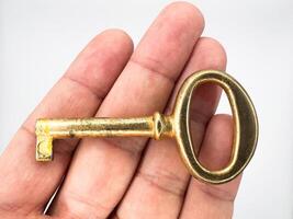 Golden metal key from an old chest lies on a hand on a white background in the center of the image, top view photo