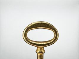 Golden metal key from an old chest on a white background in the center of the image top view photo