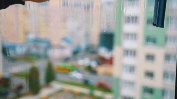 Man's hand with special brush cleaning window. Worker is washing dirty window glass with a liquid and wiping it in a flat of multi-storey building. video