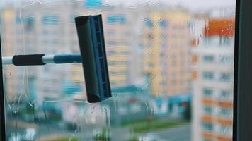 Cleaning dirty window with solution. Worker using household brush to wash window with special liquid inside. Blurred multi-storey building backdrop. video
