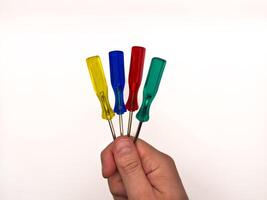 Man hand and four small colored plastic screwdrivers on a white background. copy space, flay lay, top view photo