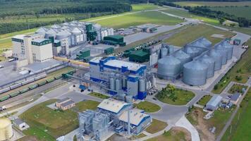 Contemporary factory on green nature background. Grain elevators for drying and storing crop. New industry on field. Aerial view. video